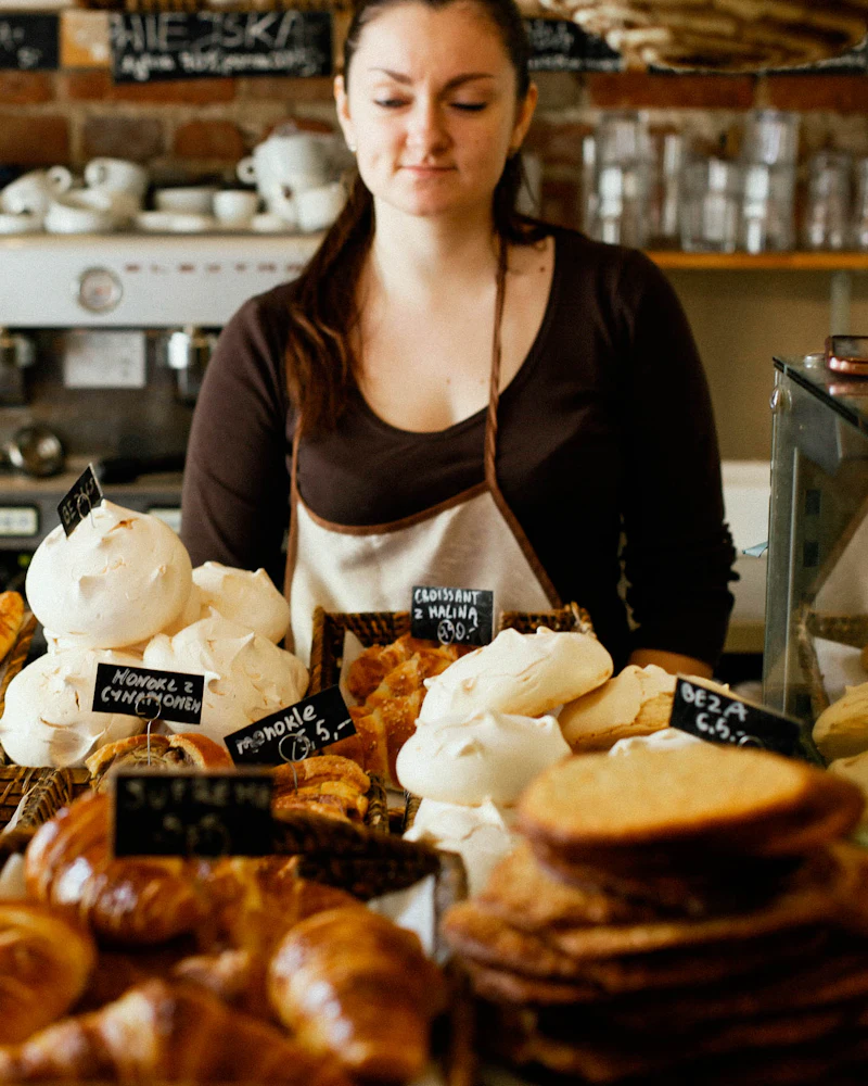 Bakery owner behind a counter full of fresh bread and pastries